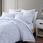 Bed with light blue floral bedding and white pillows in a bedroom setting.
