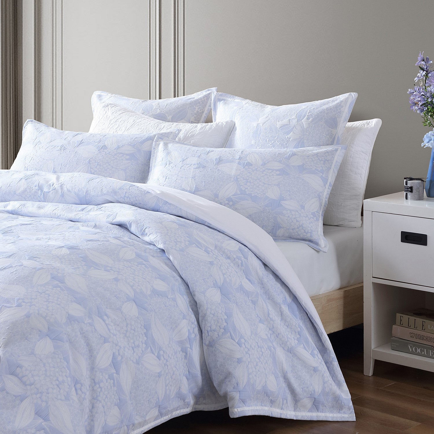 Bed with light blue floral bedding and white pillows in a bedroom setting.