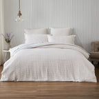 Neatly made bed with white bedding in a bedroom setting.