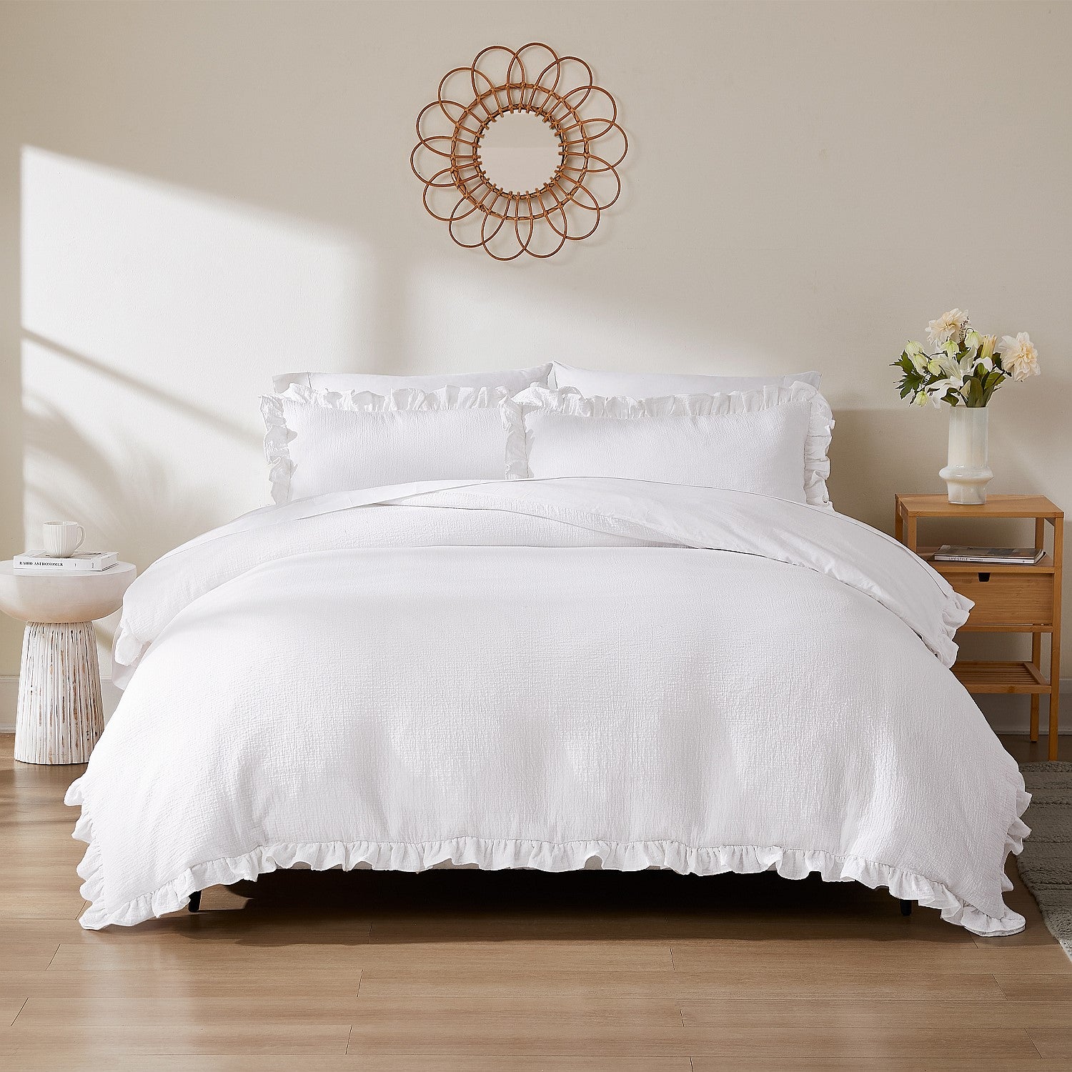 White bedding set on a bed in a bedroom with a decorative wall piece and side table.