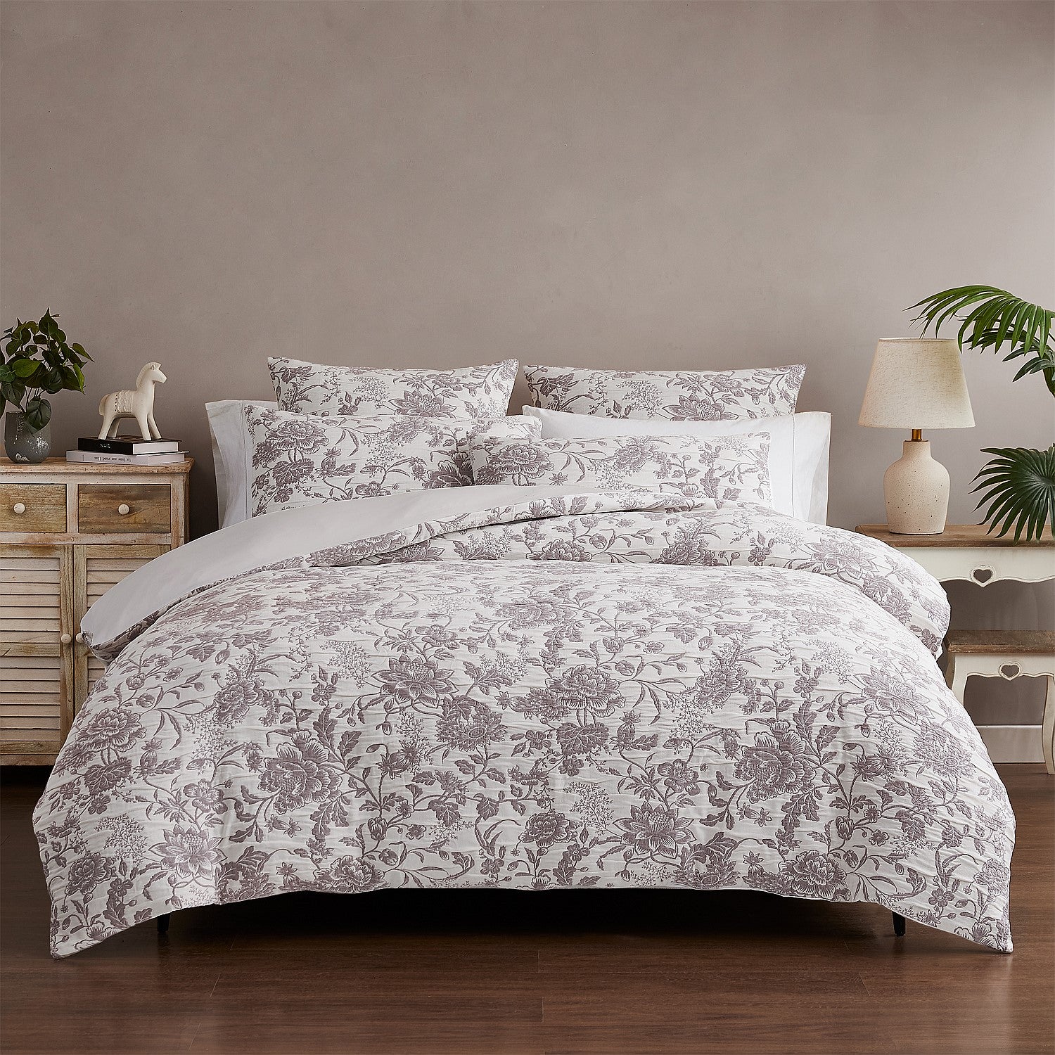 Floral patterned bedding set on a bed in a bedroom setting with side tables and decor.