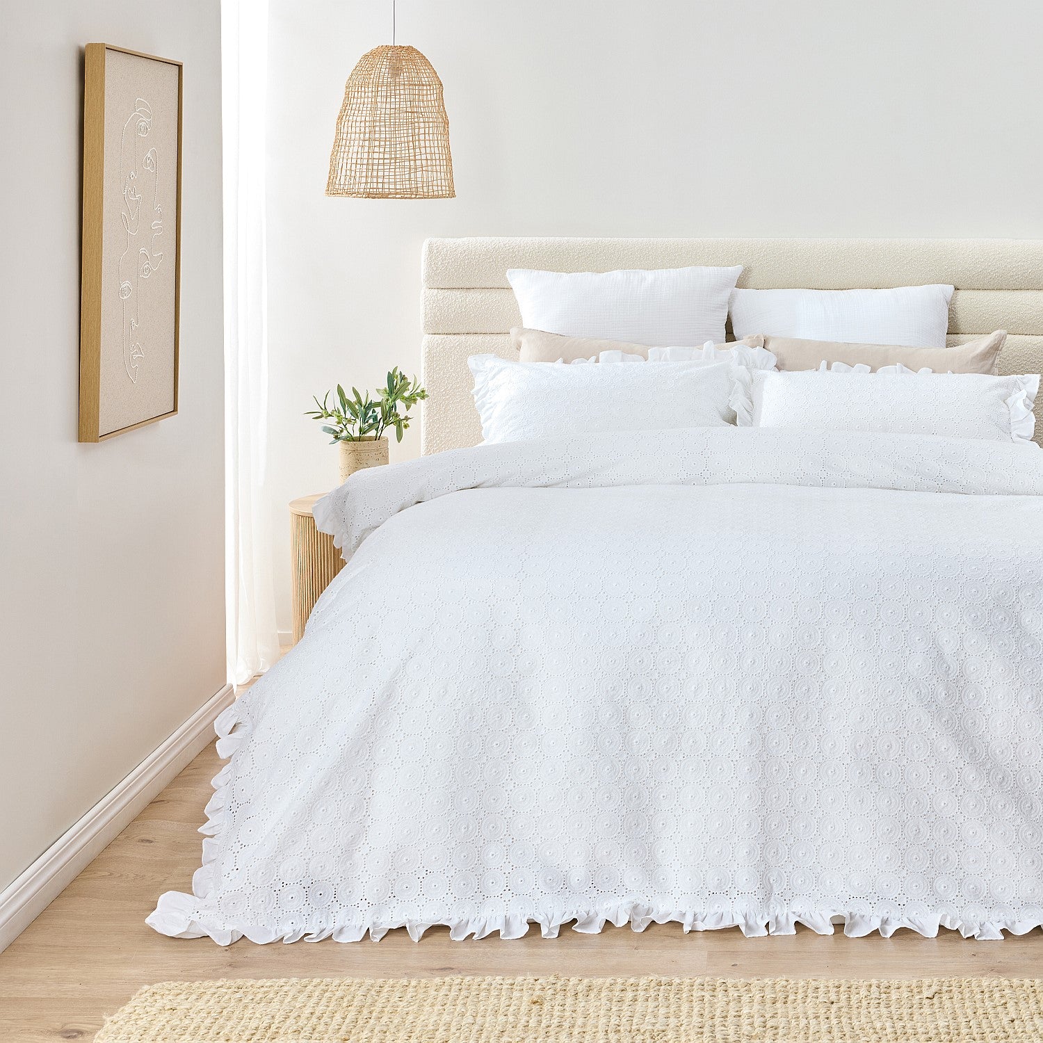 White textured duvet cover on a bed in a bright bedroom with a lamp and plant.