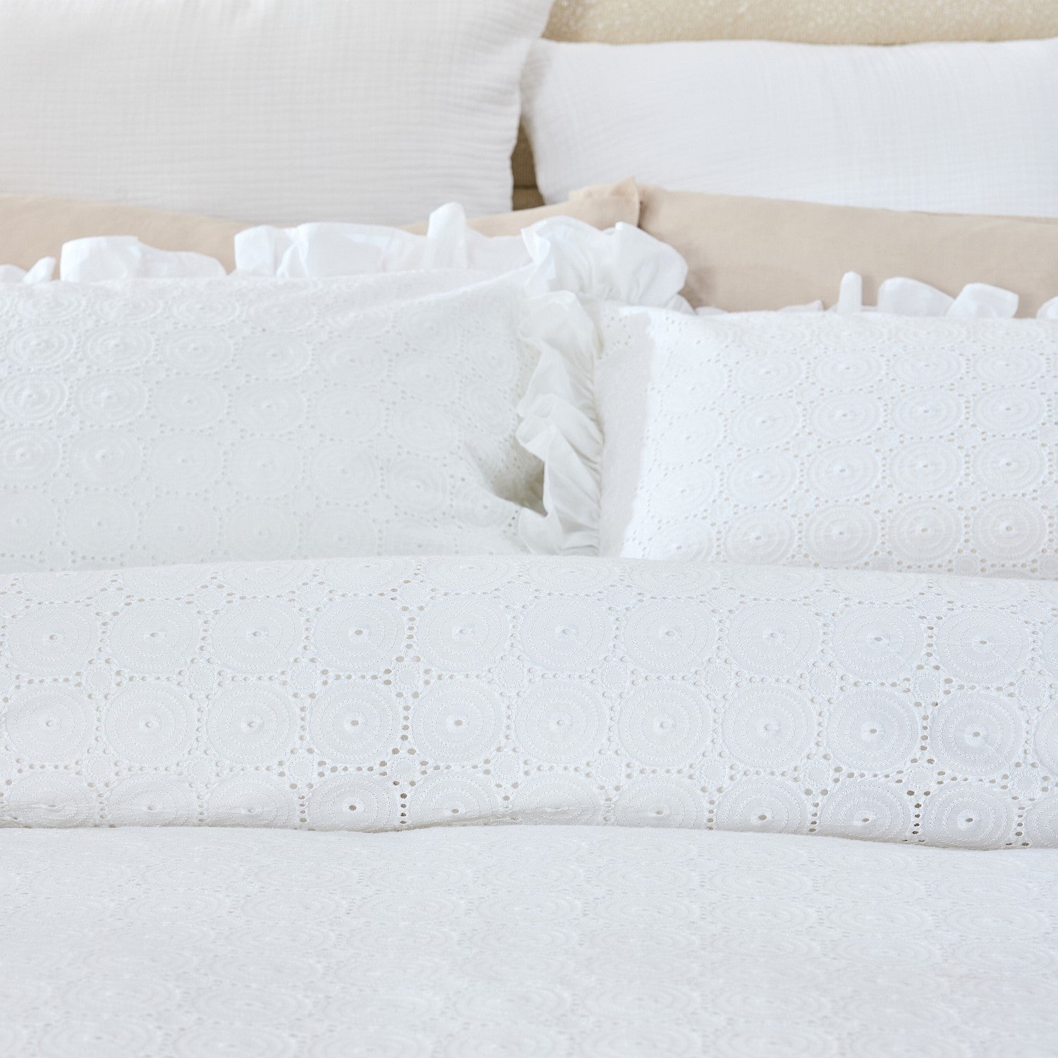 Close-up of white textured bedding with ruffled edges on a bed.