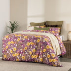 Floral bedding set on a bed in a bedroom with a lamp and plant.