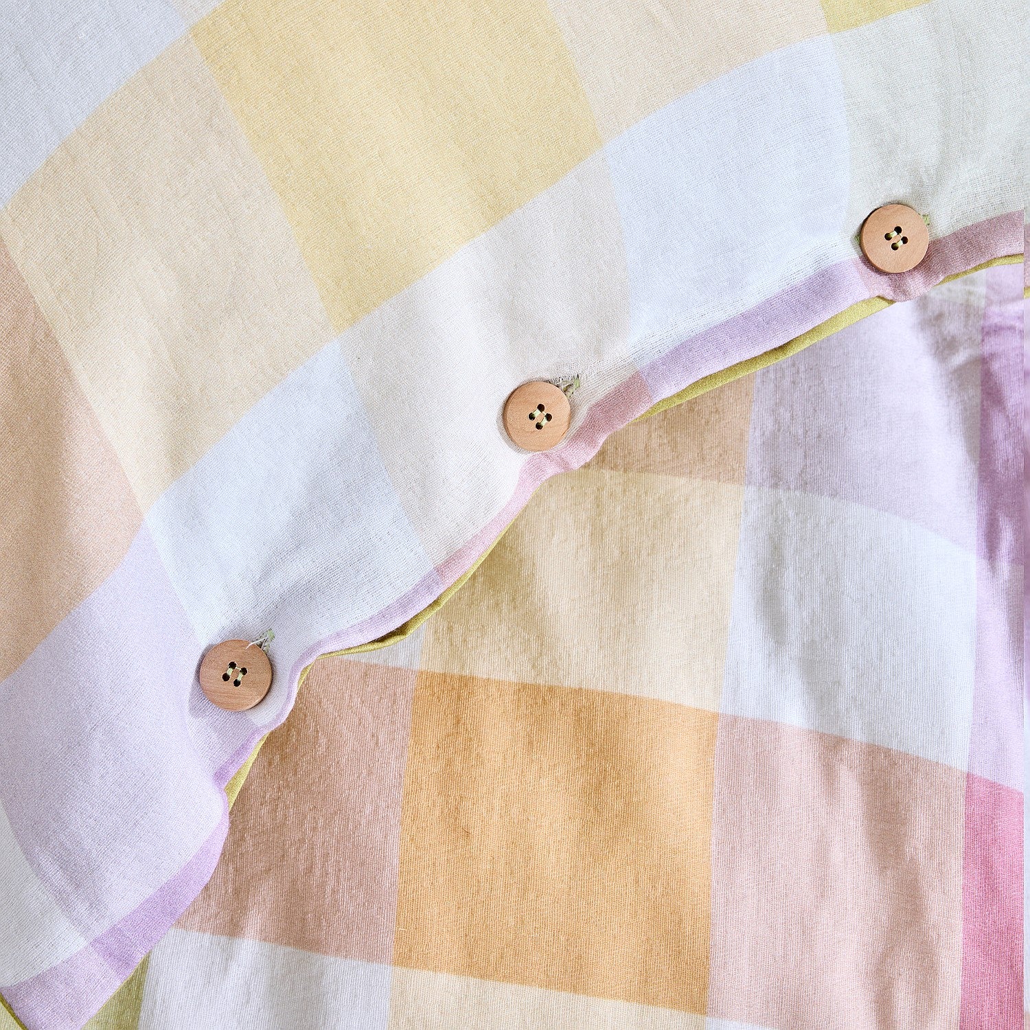 Close-up of a checkered fabric with buttons on a yellow and pink background