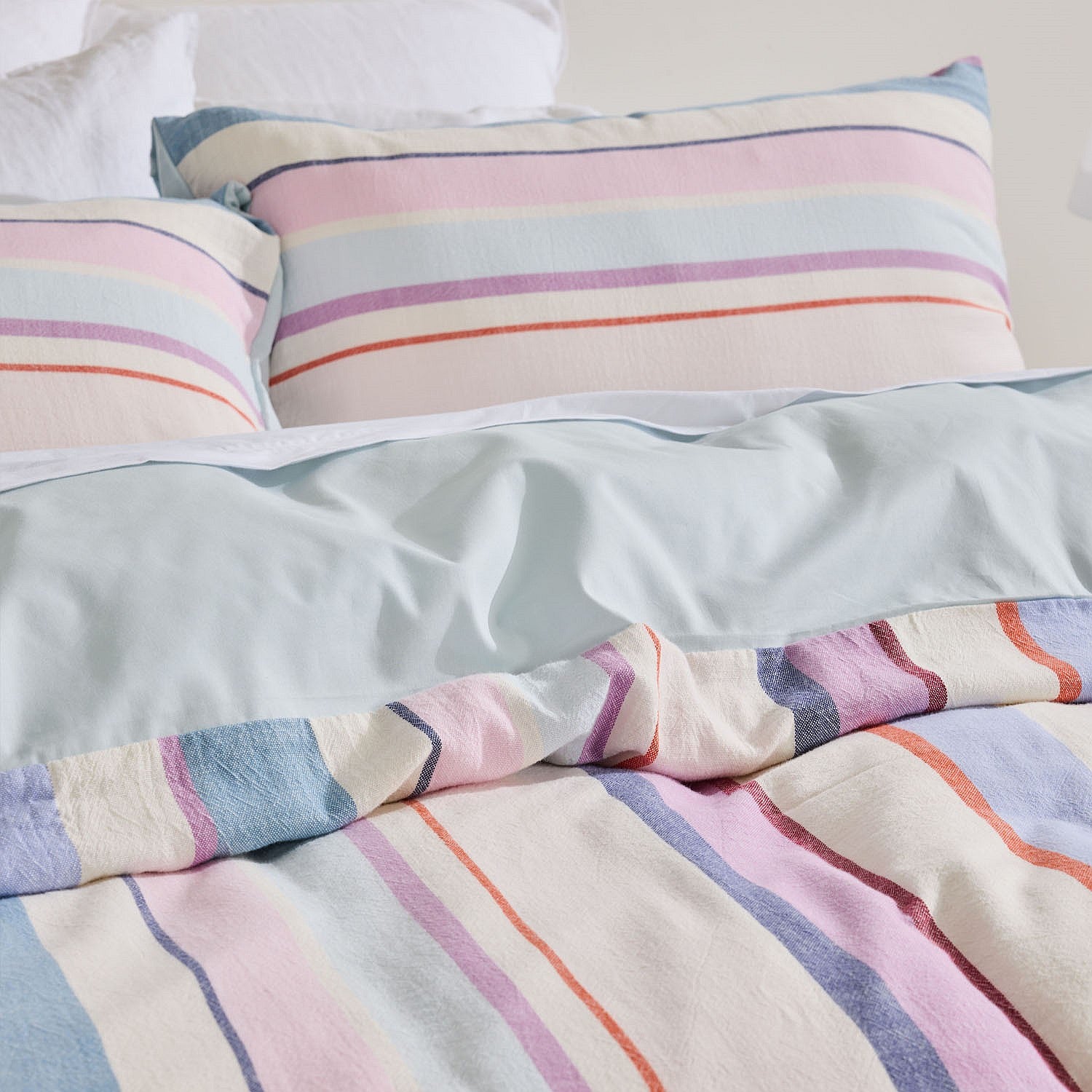 Striped bedding with pastel colors on a bed.
