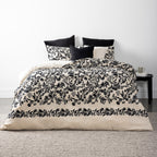 Bed with black and white floral bedding in a minimalistic room.