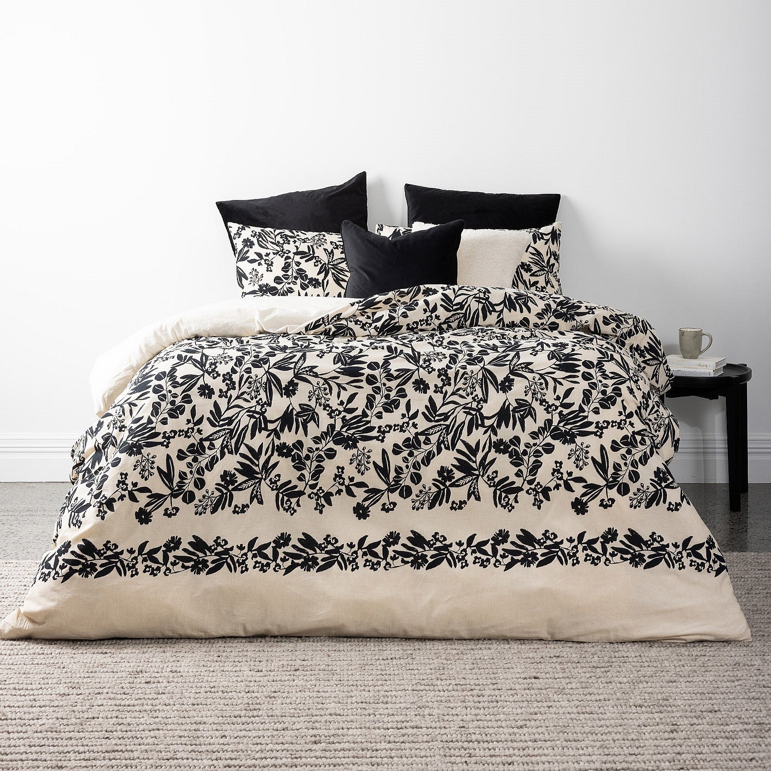 Bed with black and white floral bedding in a minimalistic room.