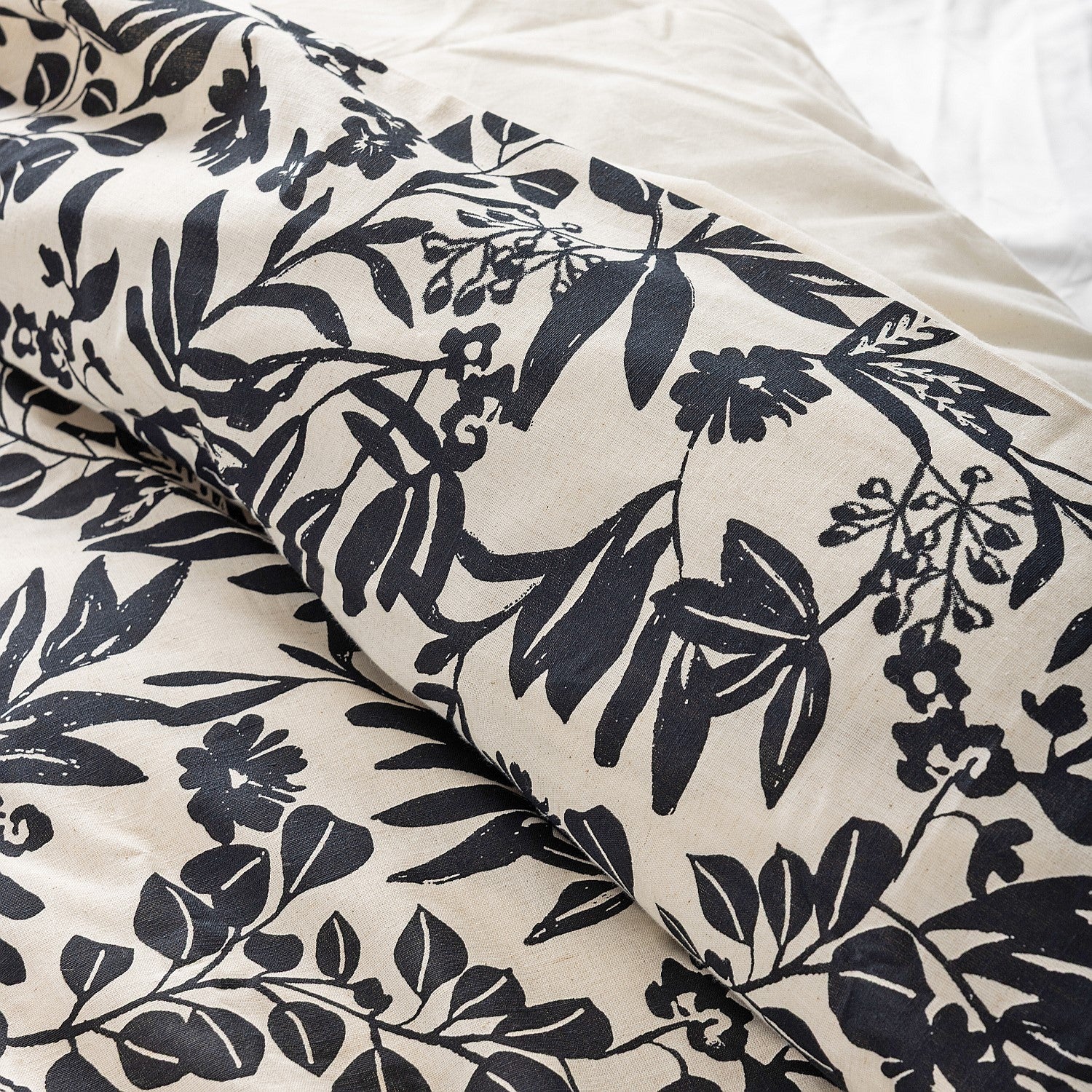 Floral patterned fabric with black leaves and flowers on a white background