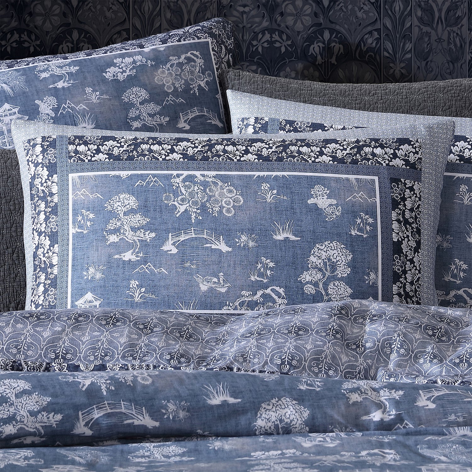 Set of blue patterned pillows and bedspread on a dark background