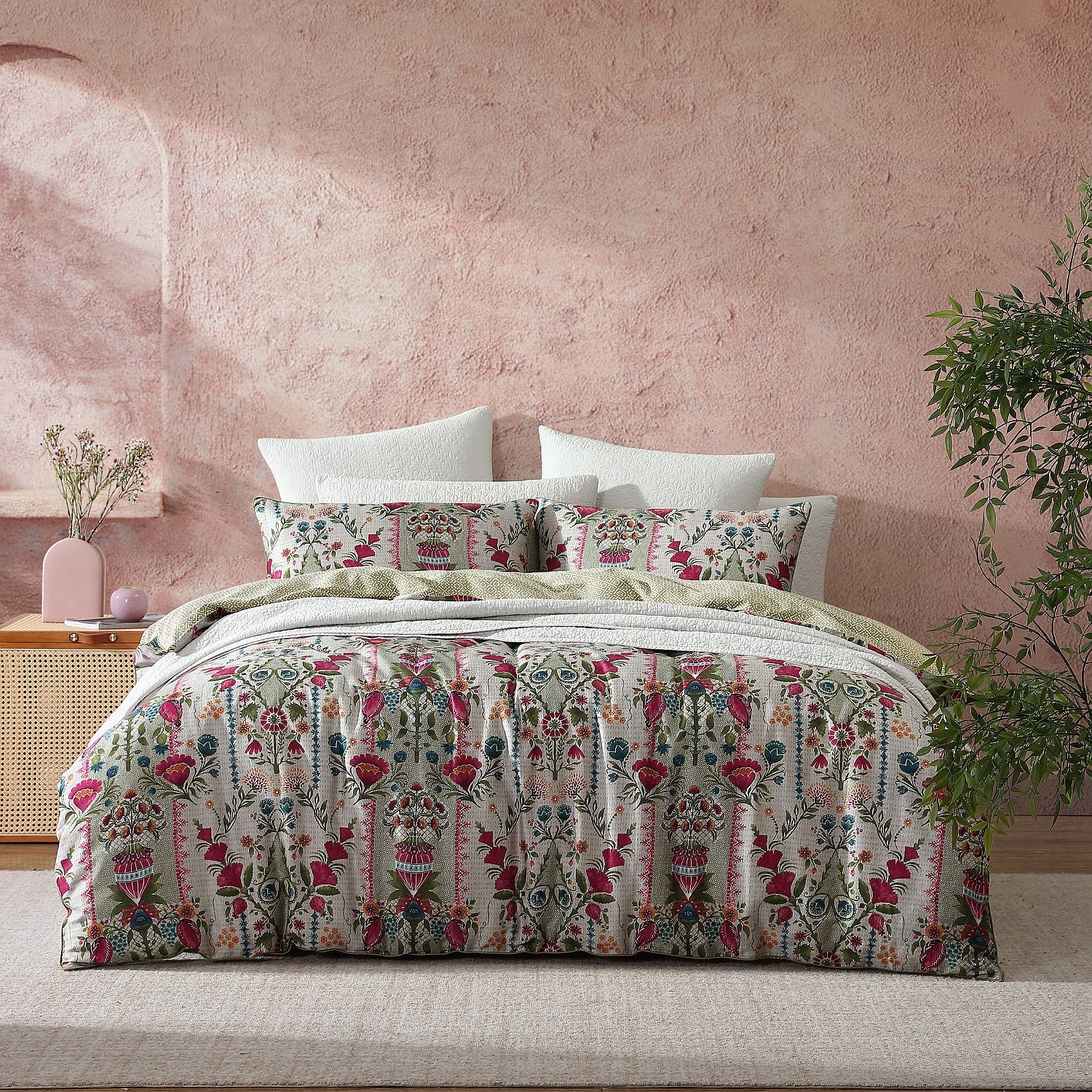 Bed with patterned bedding against a pink wall