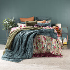 Colorful bedding set on a bed with a decorative headboard against a dark green wall.
