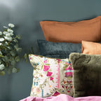 Decorative pillows with floral pattern and solid colors against a dark gray wall.