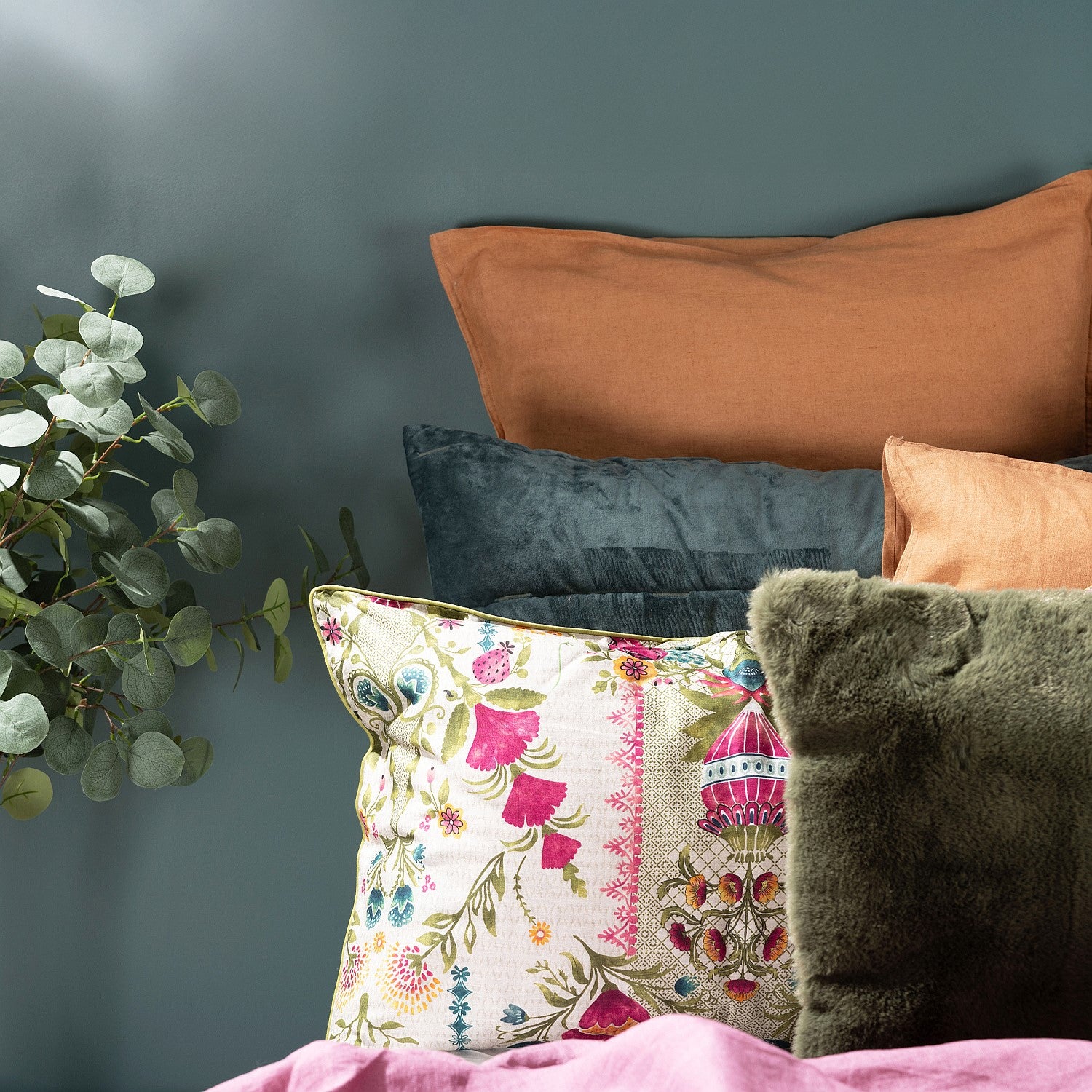 Decorative pillows with floral pattern and solid colors against a dark gray wall.