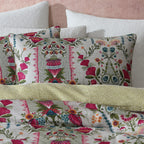 Floral patterned pillows on a bed with a pink wall background