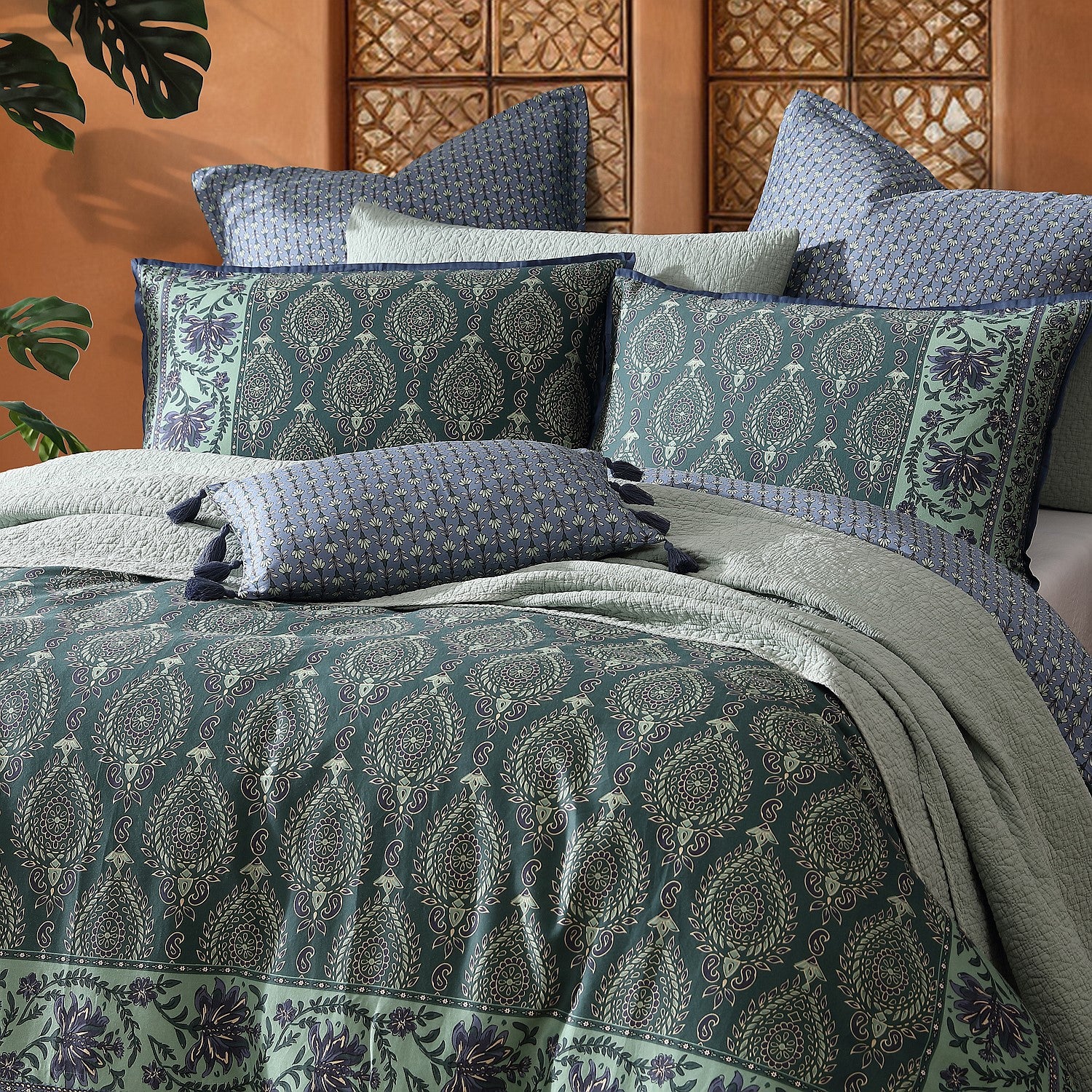 Patterned bedding set with pillows on a bed against a wooden wall.