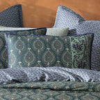 Patterned bedding set with pillows on a bed against an orange wall.