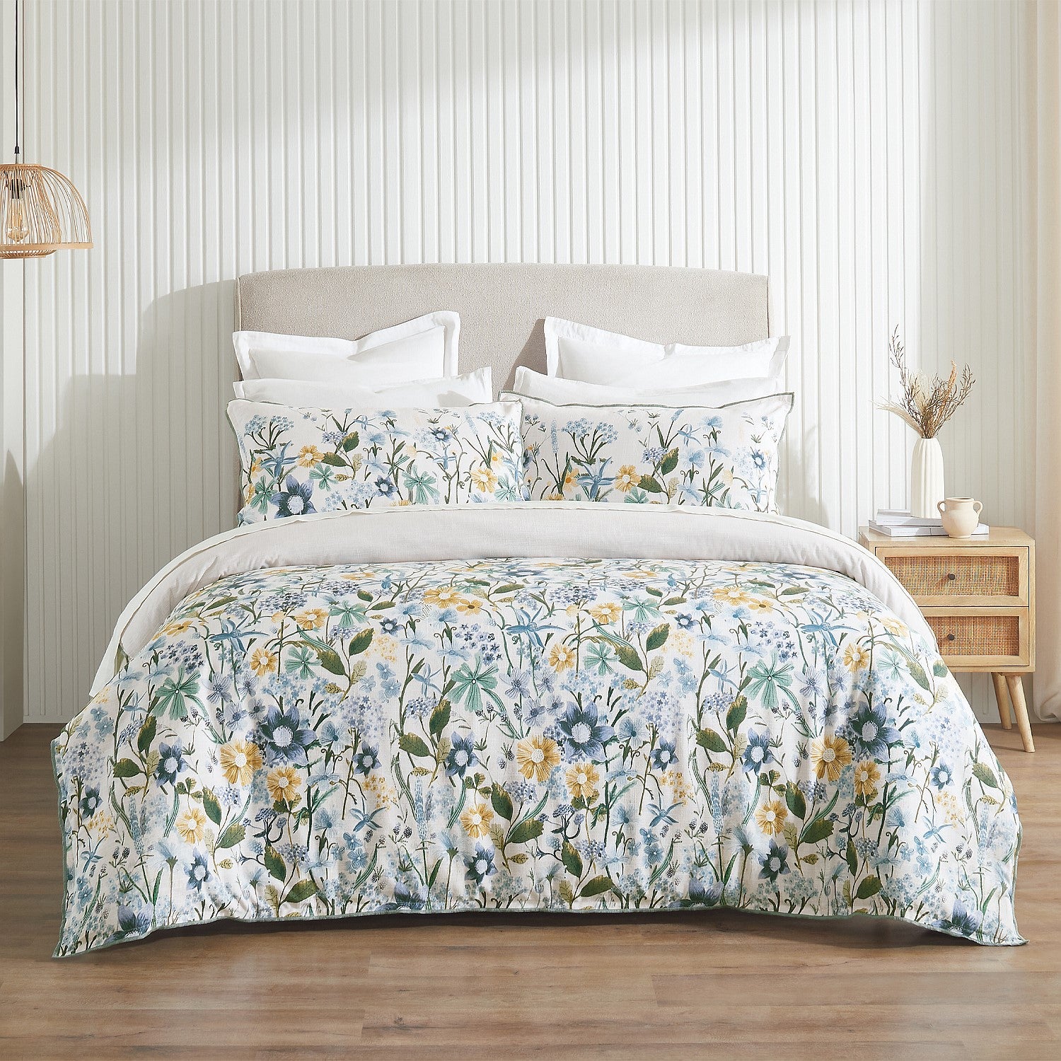 Floral bedding set on a bed in a bedroom with a wooden nightstand.