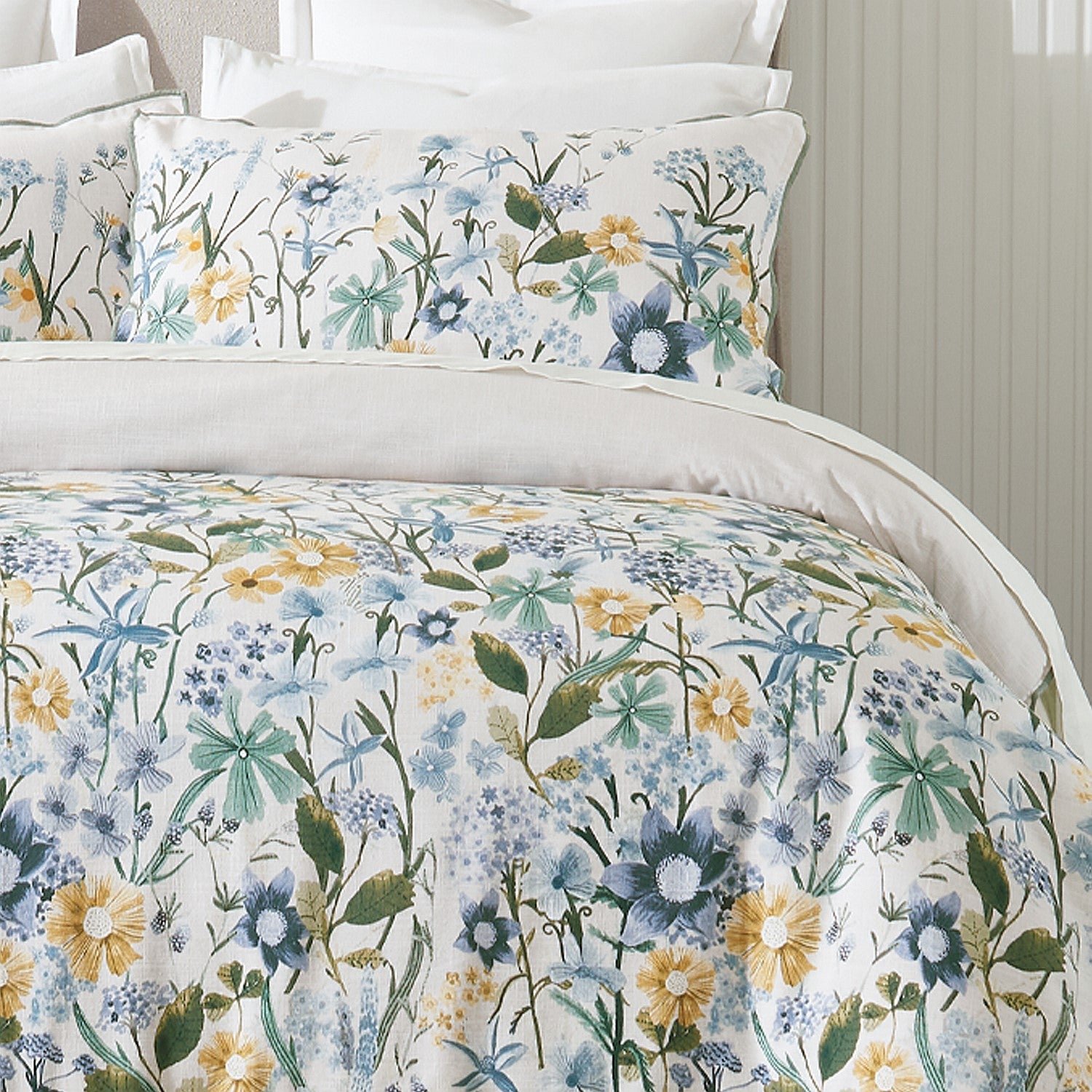 Floral bedding set with blue, yellow, and green flowers on a bed.