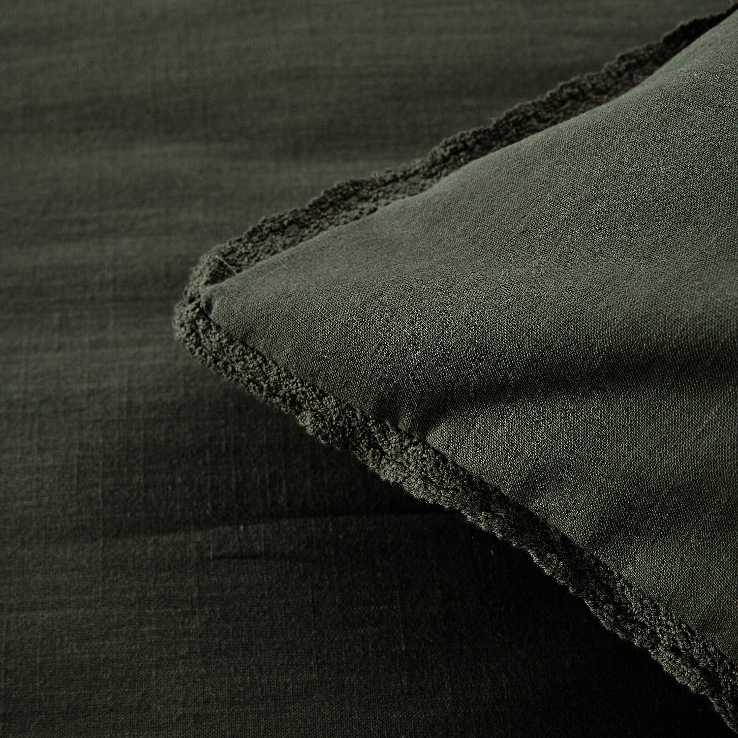 Dark green fabric with a textured edge on a matching background