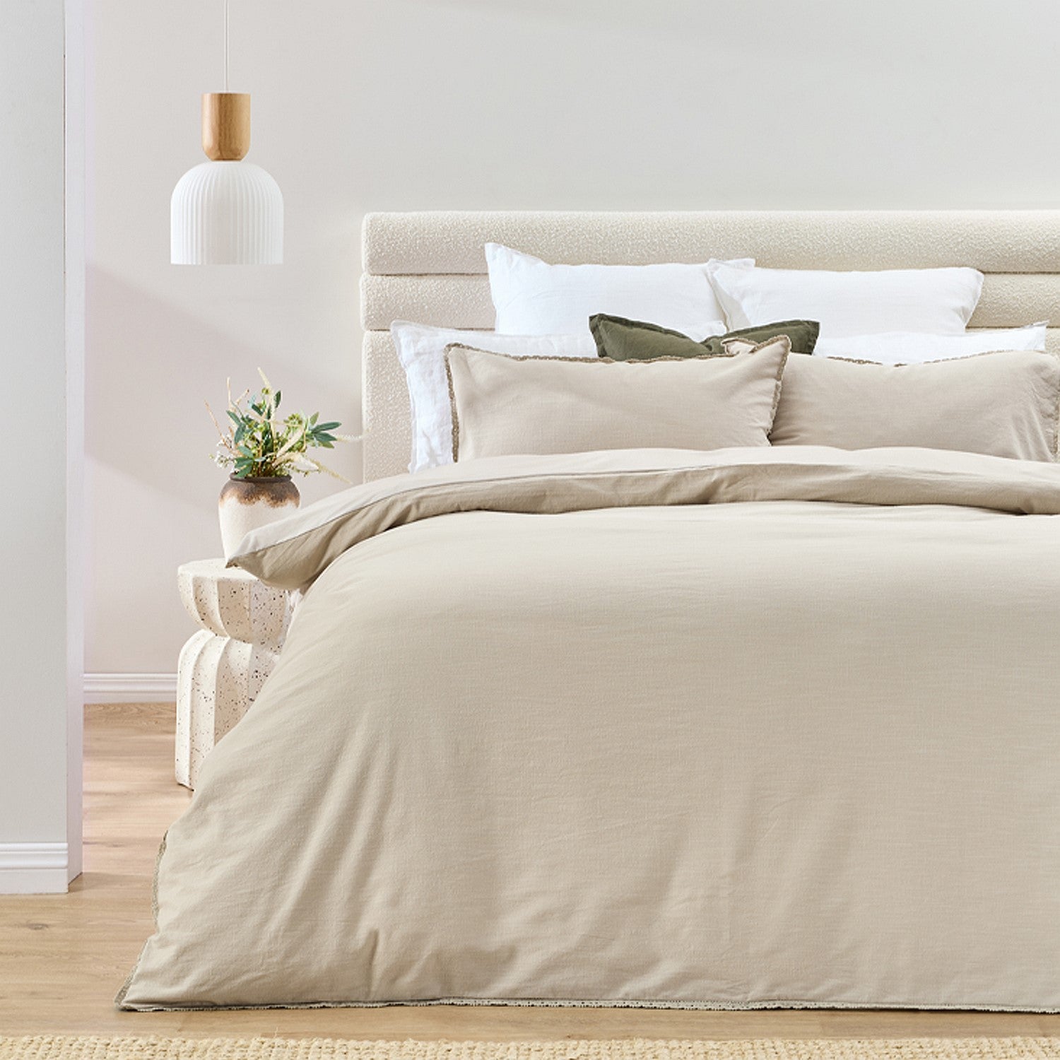 Neatly made bed with beige bedding in a bedroom setting.