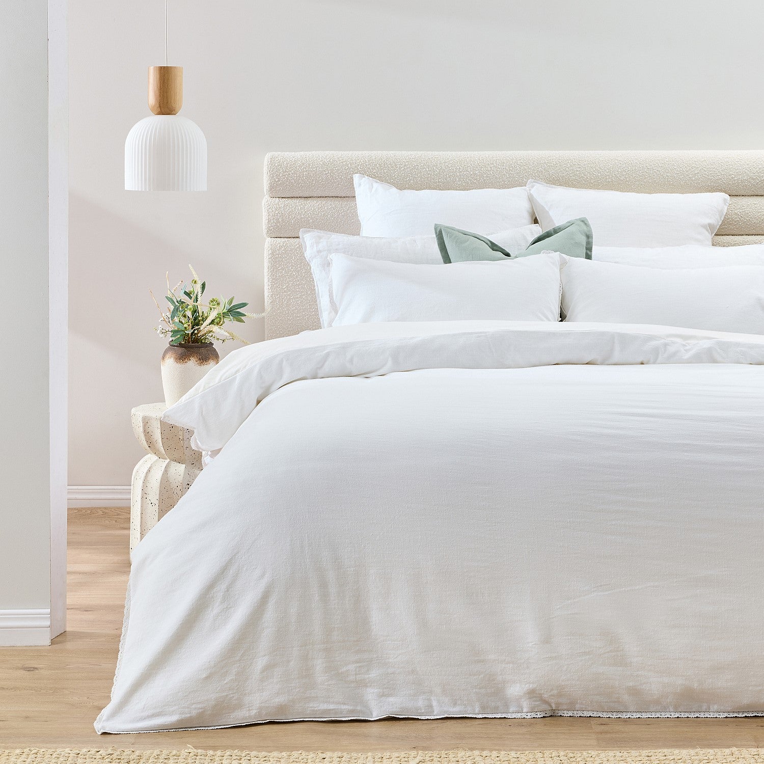 Neatly made bed with white bedding in a bright bedroom.