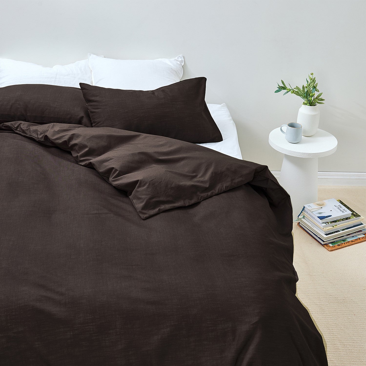 Brown bedding set on a bed with a white nightstand and books in the background.