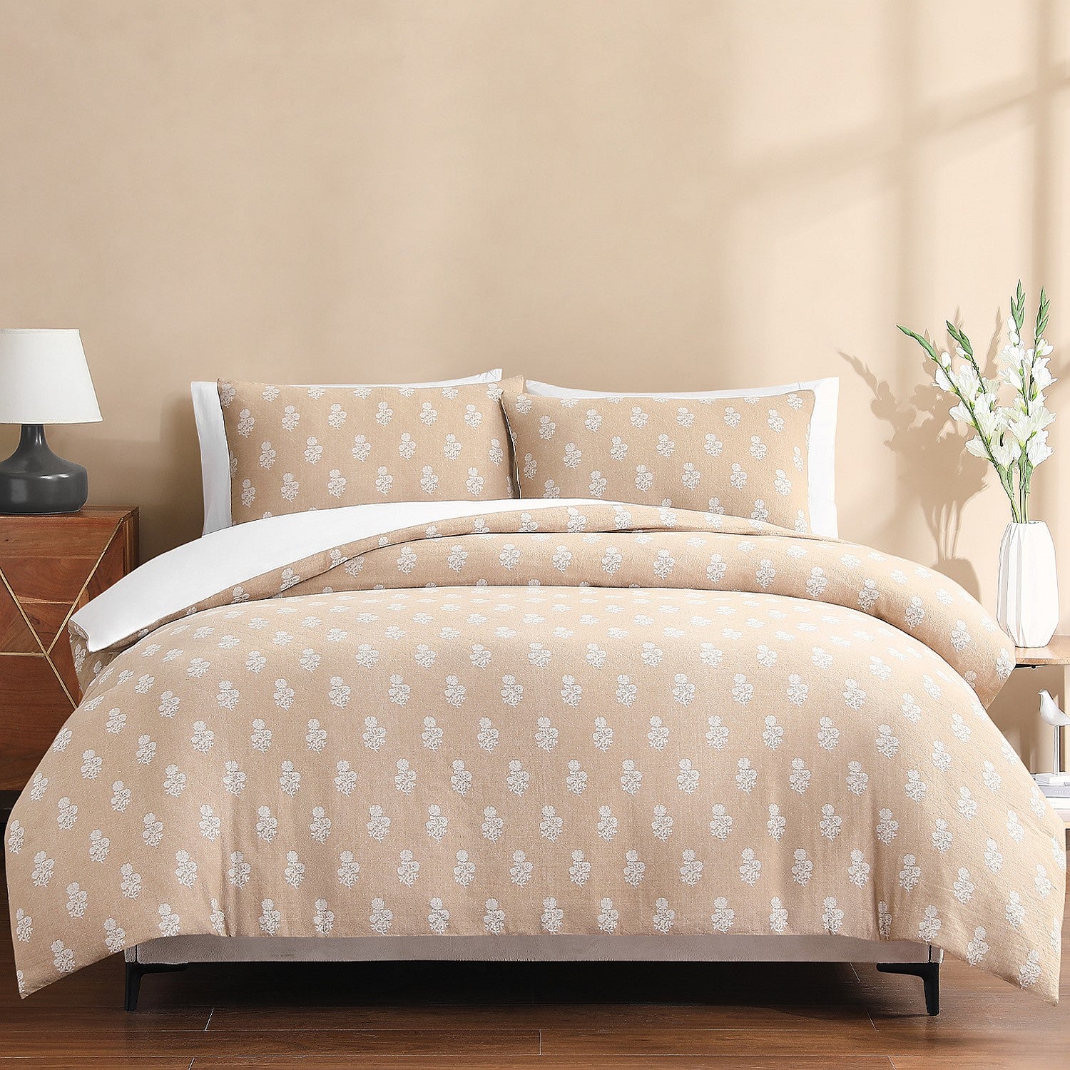 Beige floral patterned bedding set on a bed in a bedroom setting.