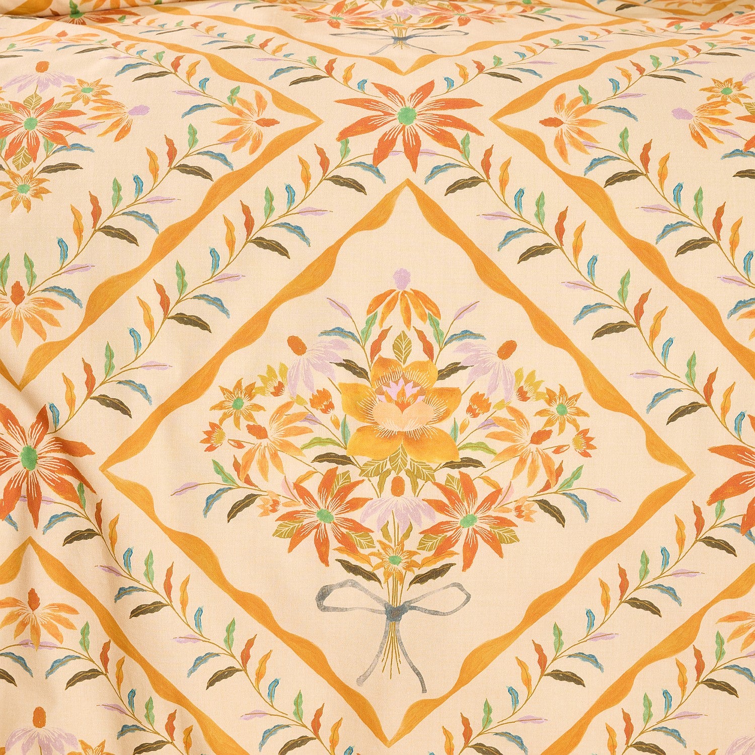 Close-up of floral patterned fabric with orange and green colors on a beige background