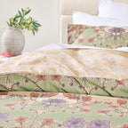 Floral patterned bedding set on a bed with a vase of flowers in the background.