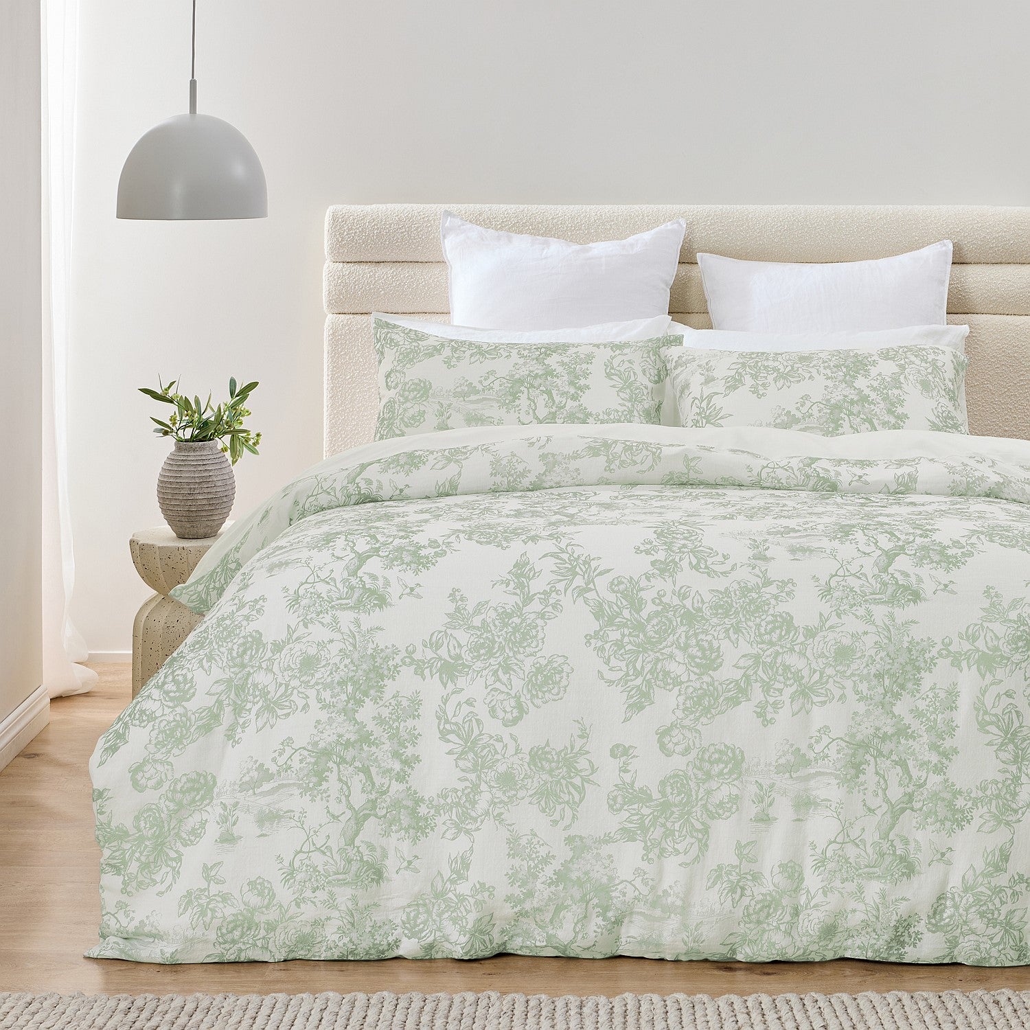 Bed with green floral patterned comforter and pillows in a bedroom setting.