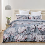 Floral bedding set on a bed in a bedroom with a lamp and plant.