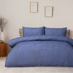 Blue patterned bedding set on a bed in a bedroom with framed art on the wall.