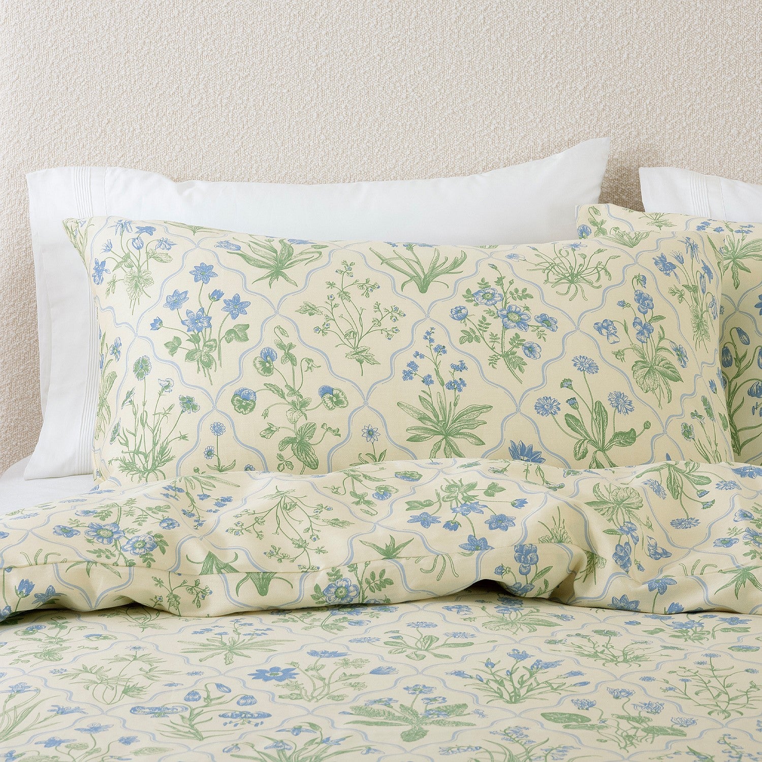 Floral patterned bed sheets and pillows on a bed with a neutral background