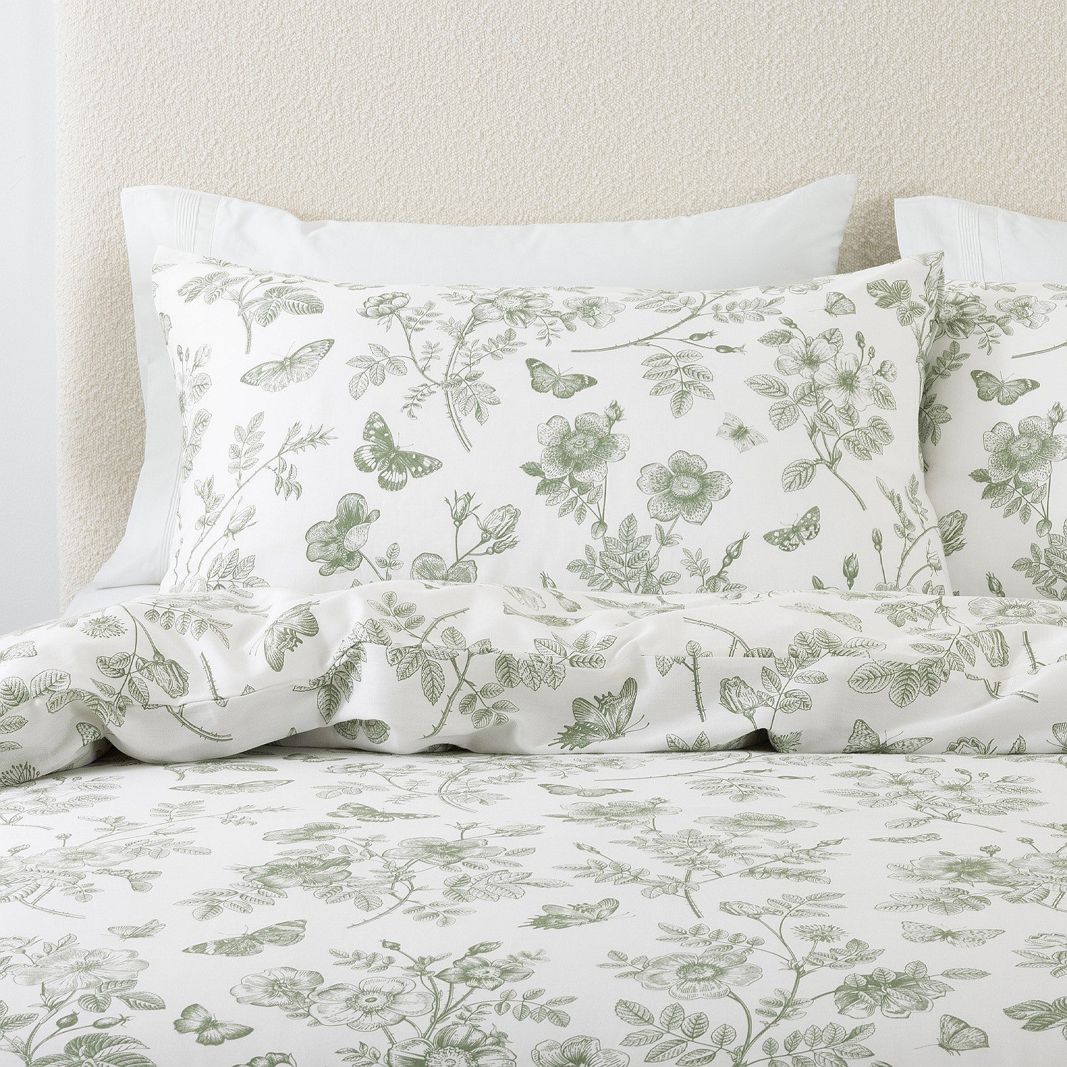 Floral and butterfly patterned bedding set on a bed with a neutral headboard.