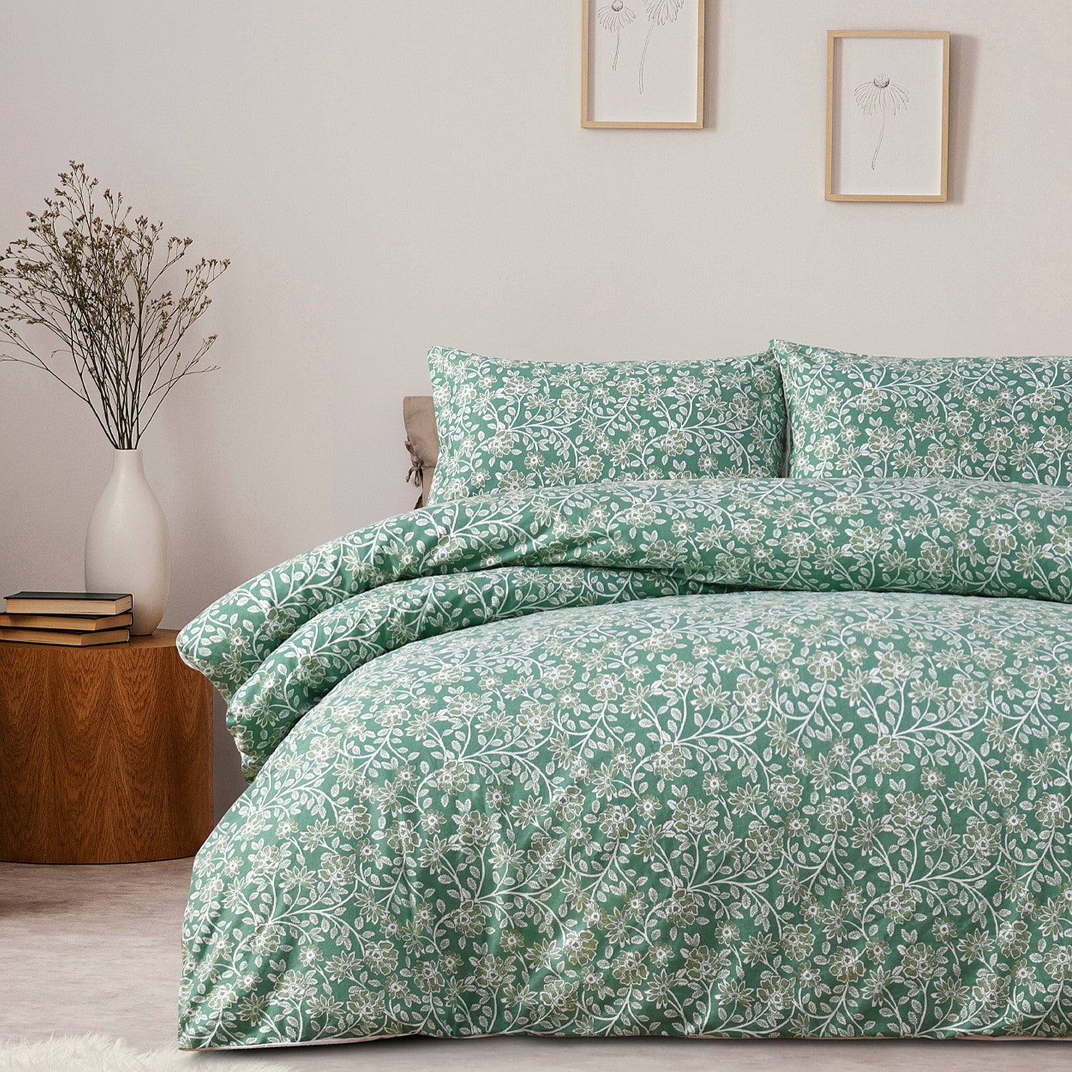 Teal floral duvet set on a bed in a bedroom with a wooden side table and decorative items.