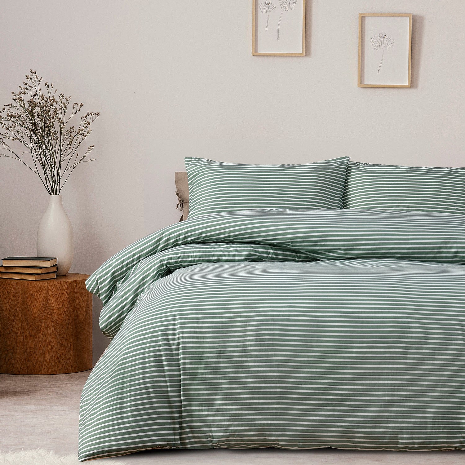 Green striped bedding set on a bed in a bedroom with a side table and decor.