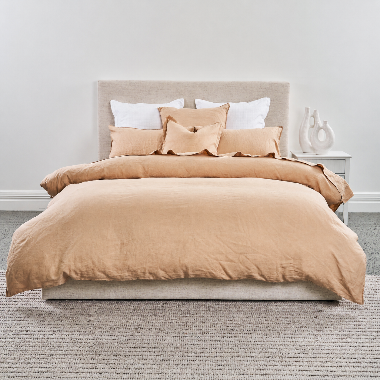 Beige duvet cover set on a bed with white pillows in a minimalistic bedroom.