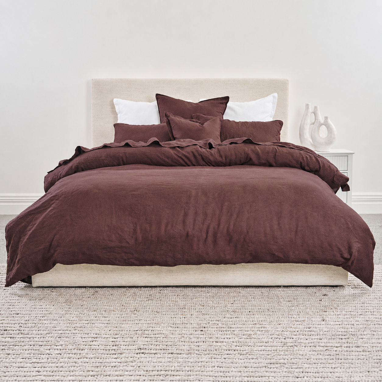 Brown duvet cover on a bed with white pillows in a minimalistic bedroom.
