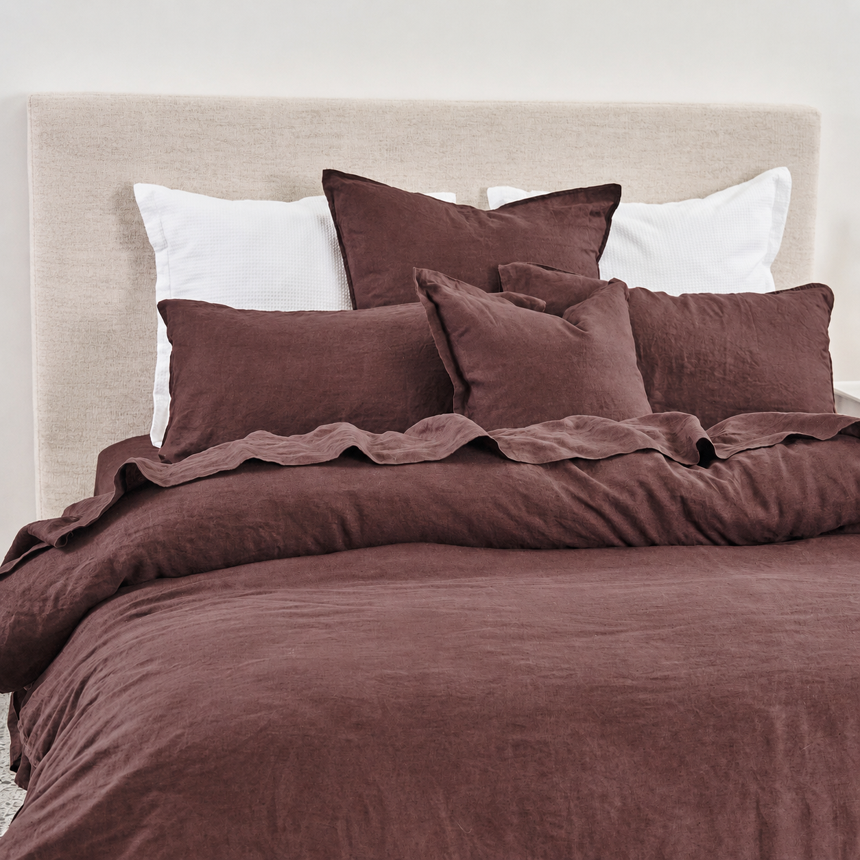 Brown bedding set with pillows on a bed against a white wall