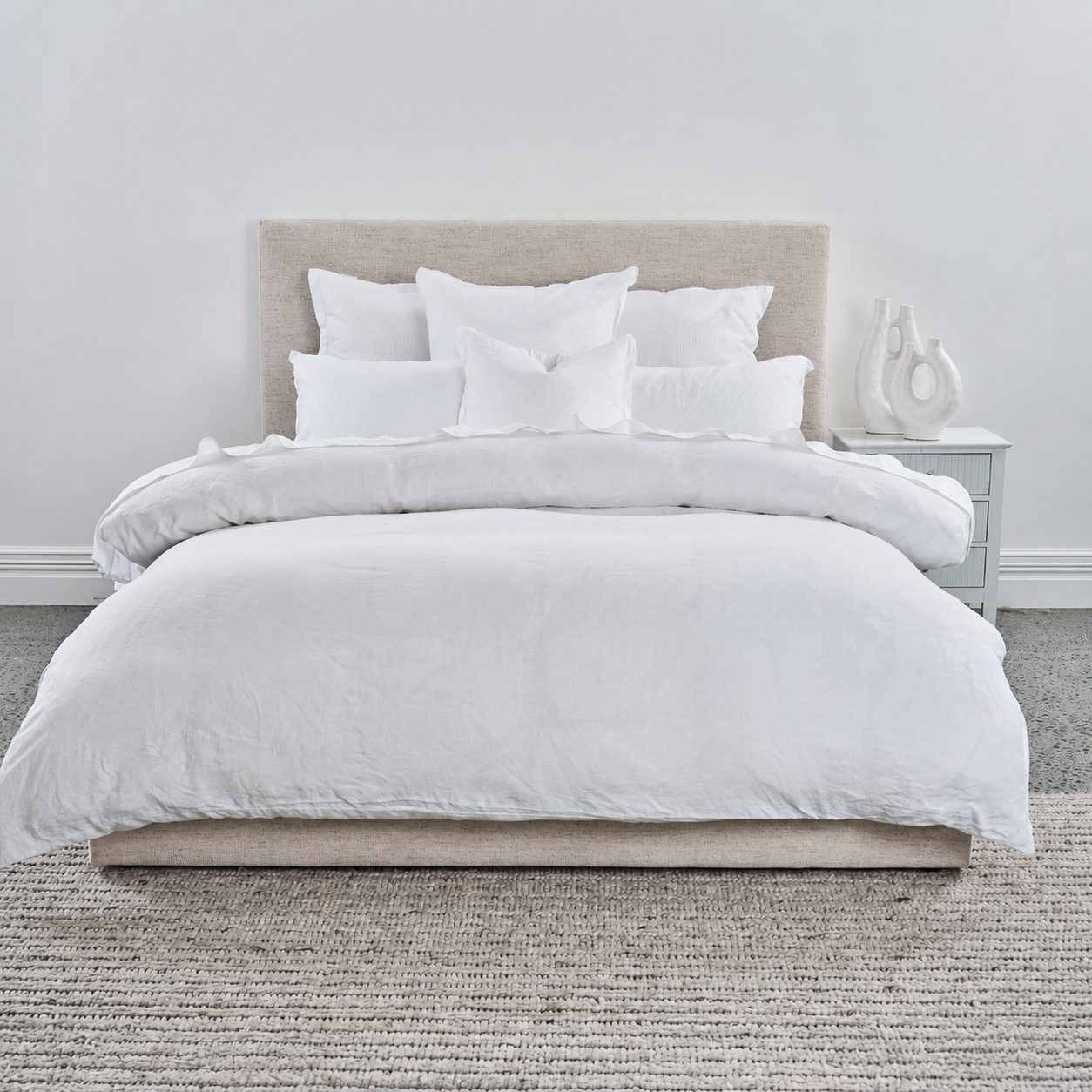 White duvet cover set on a bed with pillows in a minimalistic bedroom.