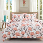 Floral patterned comforter set on a bed in a bright room with windows.