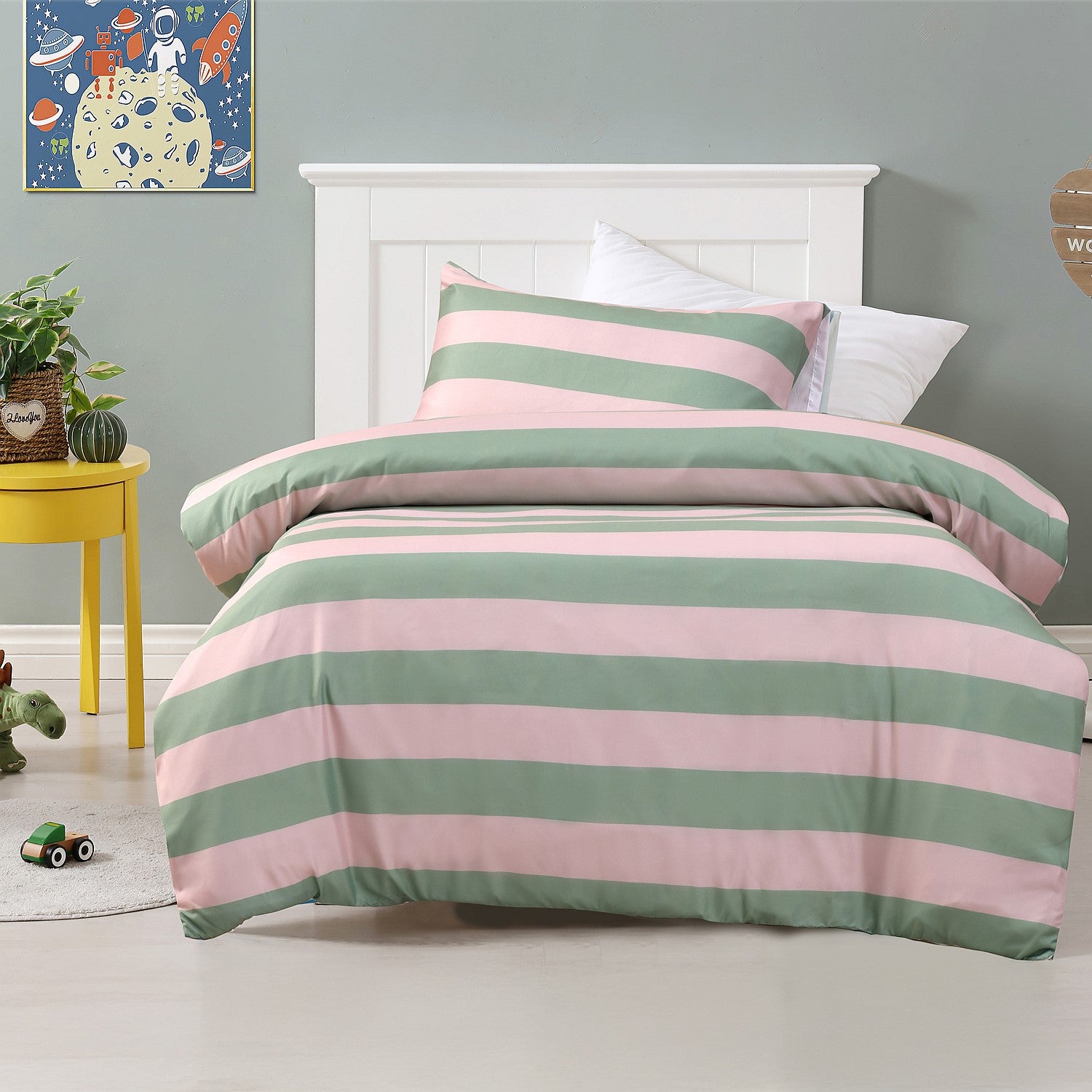 Pink and green striped duvet cover set styled on a bed with matching pillowcases in a kids bedroom.