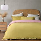 Bed with yellow bedding and pink blanket in a bedroom setting