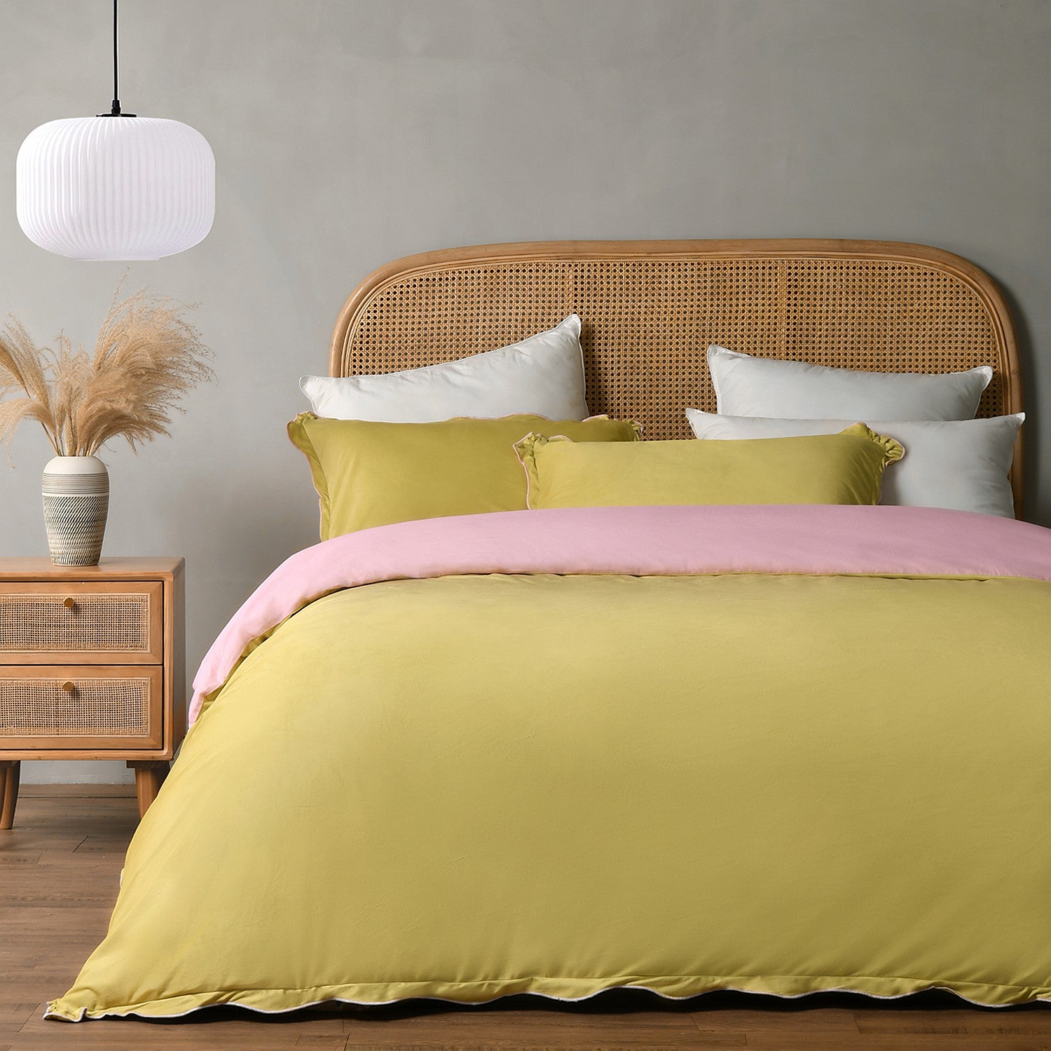 Bed with yellow bedding and pink blanket in a bedroom setting