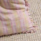 Close-up of a pink and beige striped fabric on a textured surface