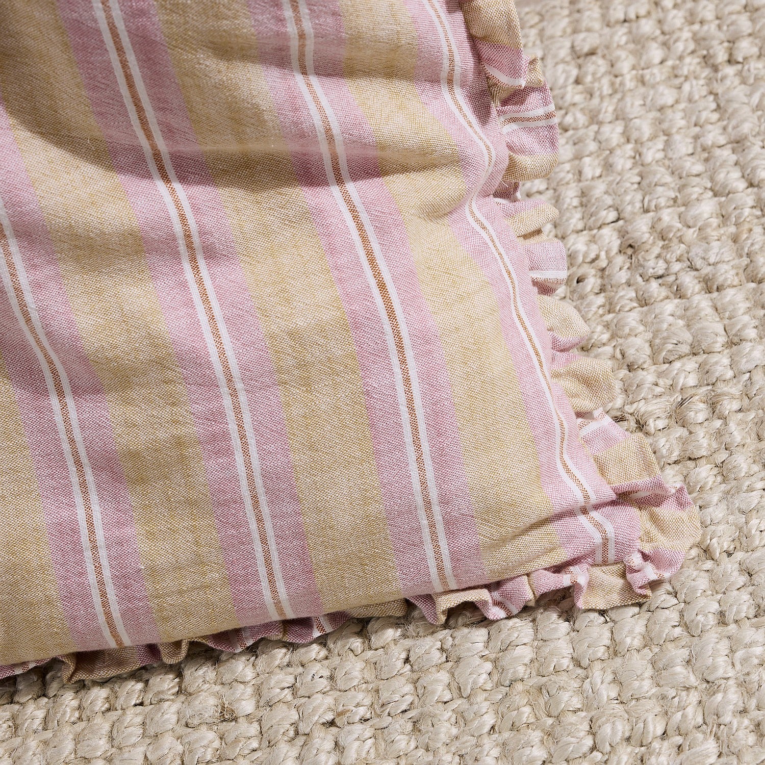Close-up of a pink and beige striped fabric on a textured surface
