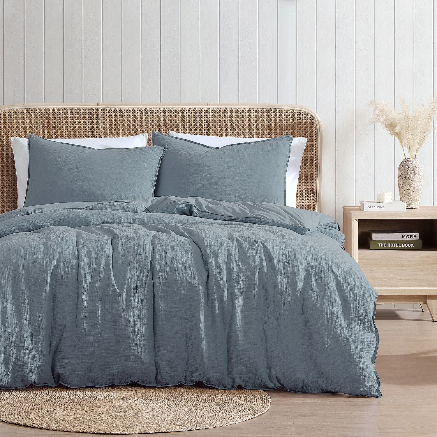 Blue textured duvet set on a bed with a wooden headboard and side table in a bedroom setting.