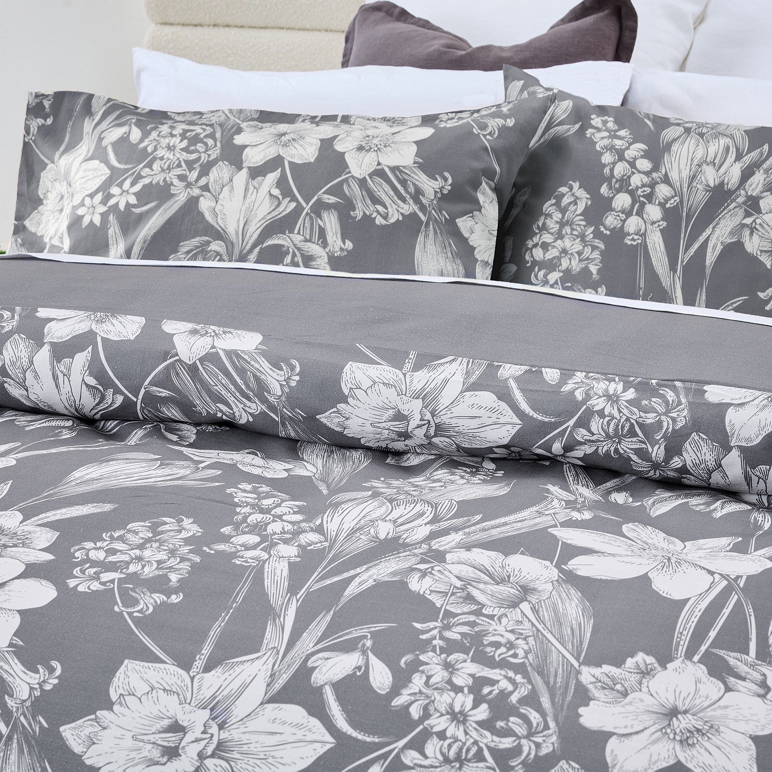 Floral bedding set with gray and white pattern on a bed.
