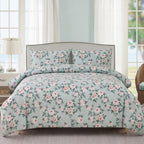 Floral bedding set on a bed in a bright room with light blue walls.